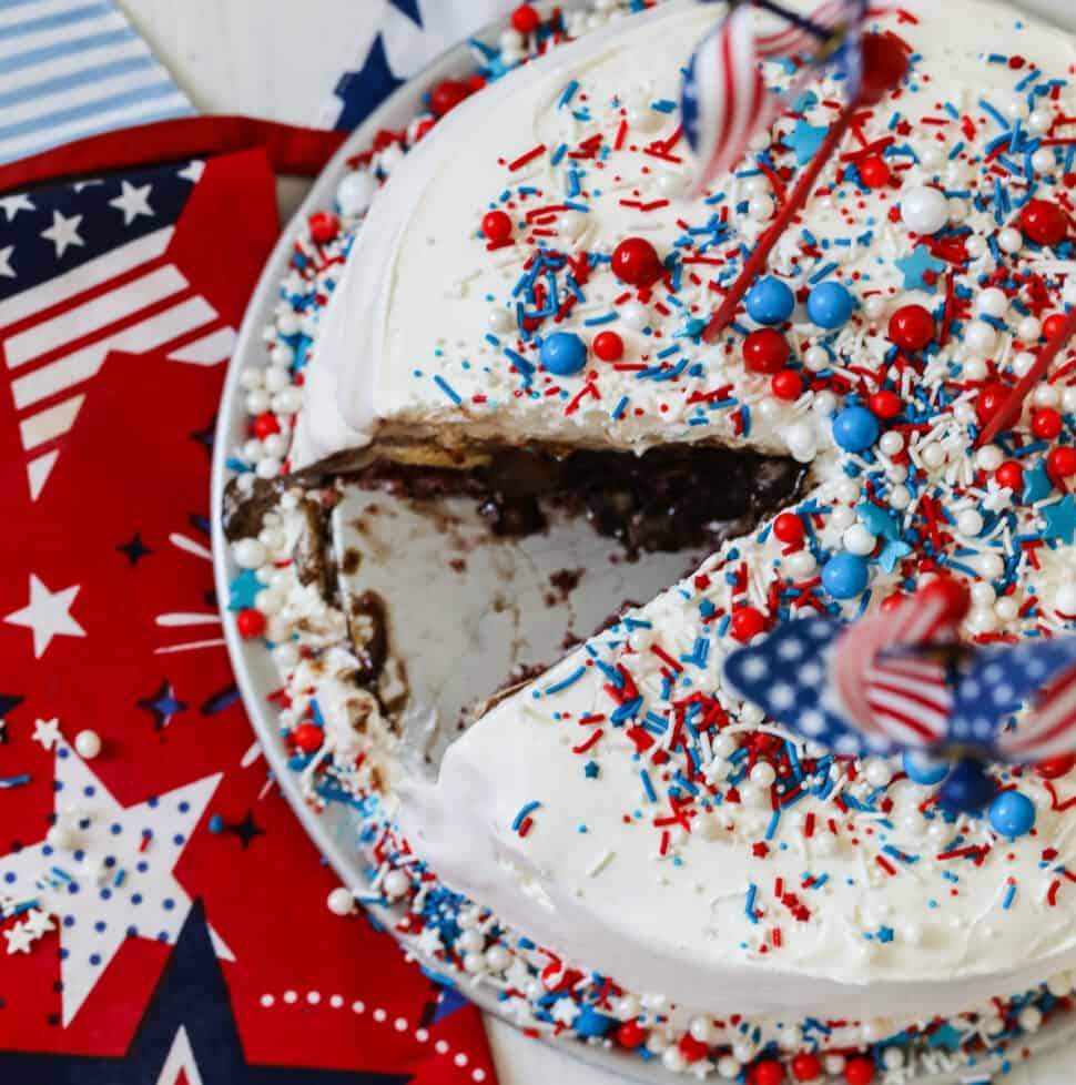 An ice cream cake with a slice removed and covered in colorful sprinkles.