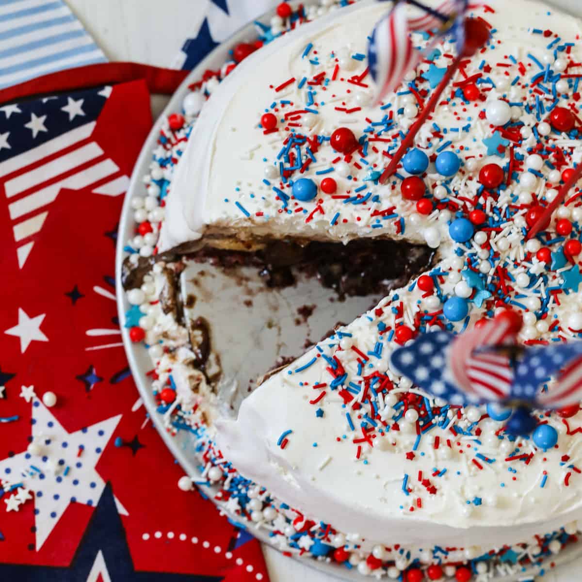 An ice cream cake with a slice removed and covered in colorful sprinkles.