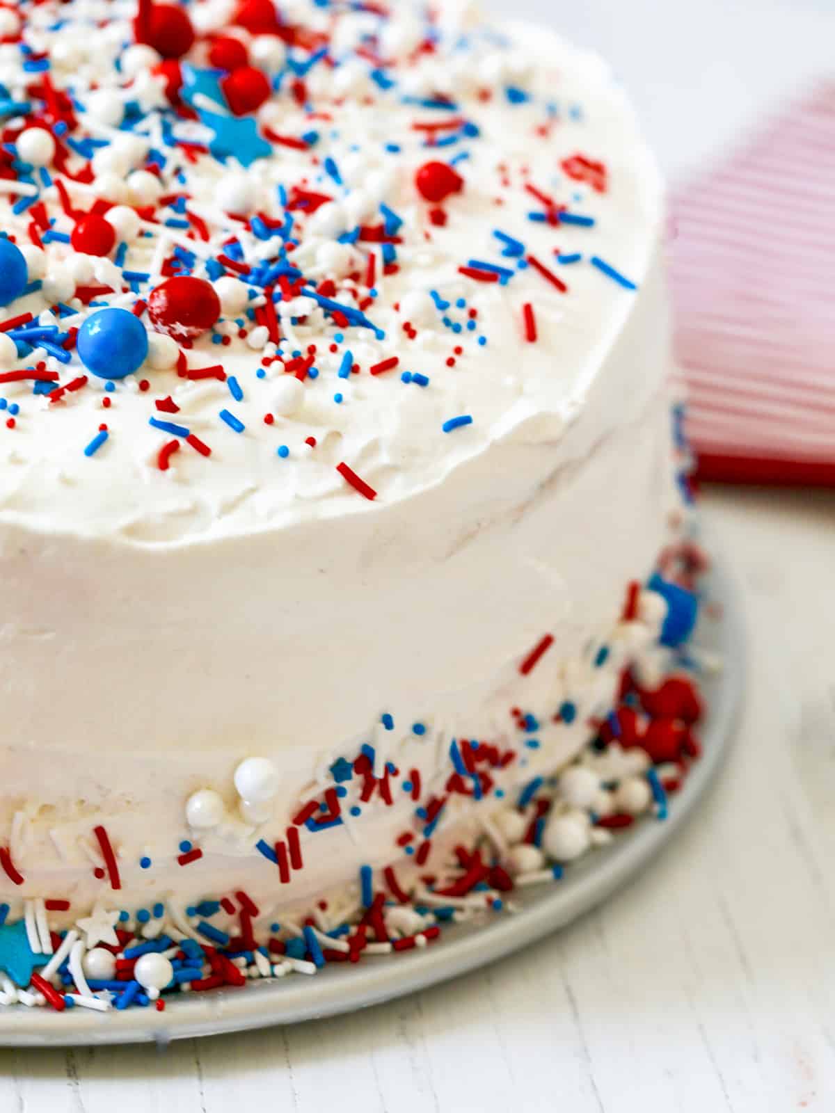 A white ice cream cake in a cake shape with red white and blue sprinkles.