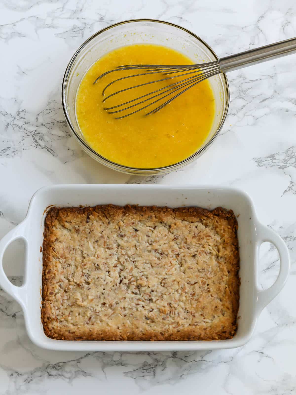 Baked crust for lemon bars with whisk in bowl of lemon bar filling.