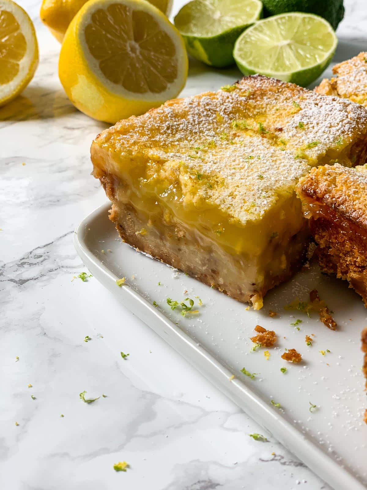 Close up of a lemon bar on a plate with crumbs.