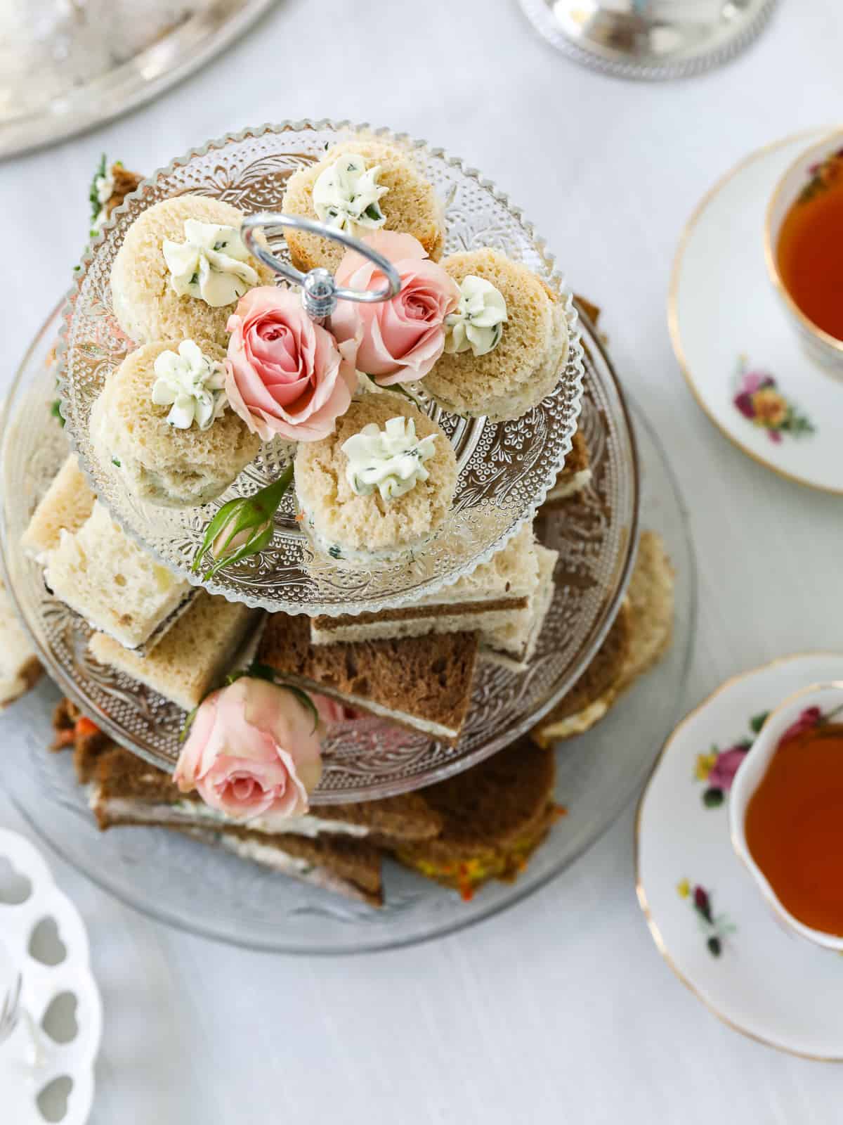 Looking down on a glass tiered tea tray stacked with various tea sandwiches.