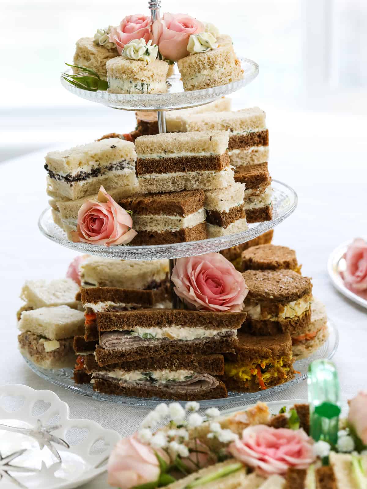 Close up of a tiered tray filled with tea sandwiches that have assorted fillings and bread.