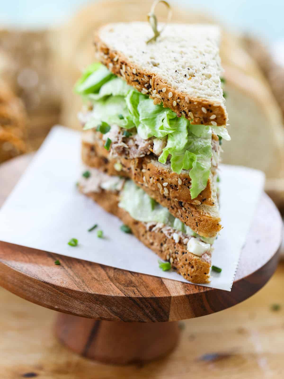 A homemade ham salad sandwich on a piece of parchment on a wood stand. 