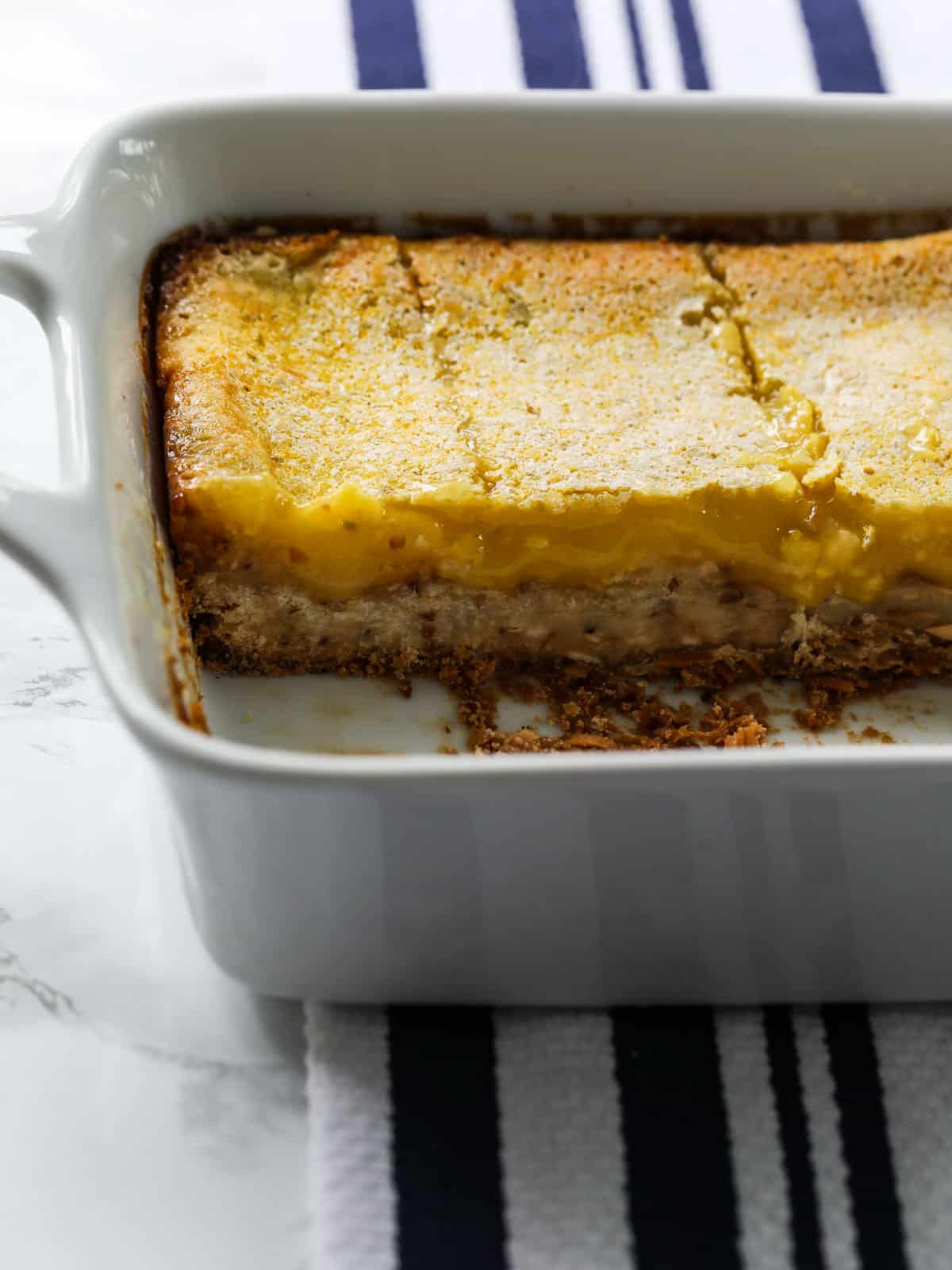 Lemon bars baked in a white dish that have lemon and lime filling on a cookie crust base.