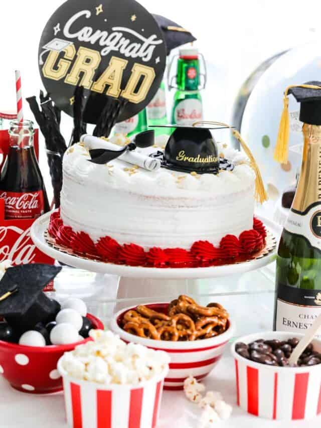 Graduation party food on a table with red and white bowls filled with snacks and a red and white decorated cake.
