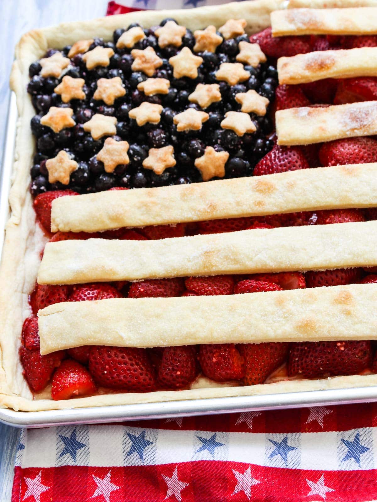 A strawberry pie baked in a sheet pan with pie crusts stripes and stars to look like an American flag. 