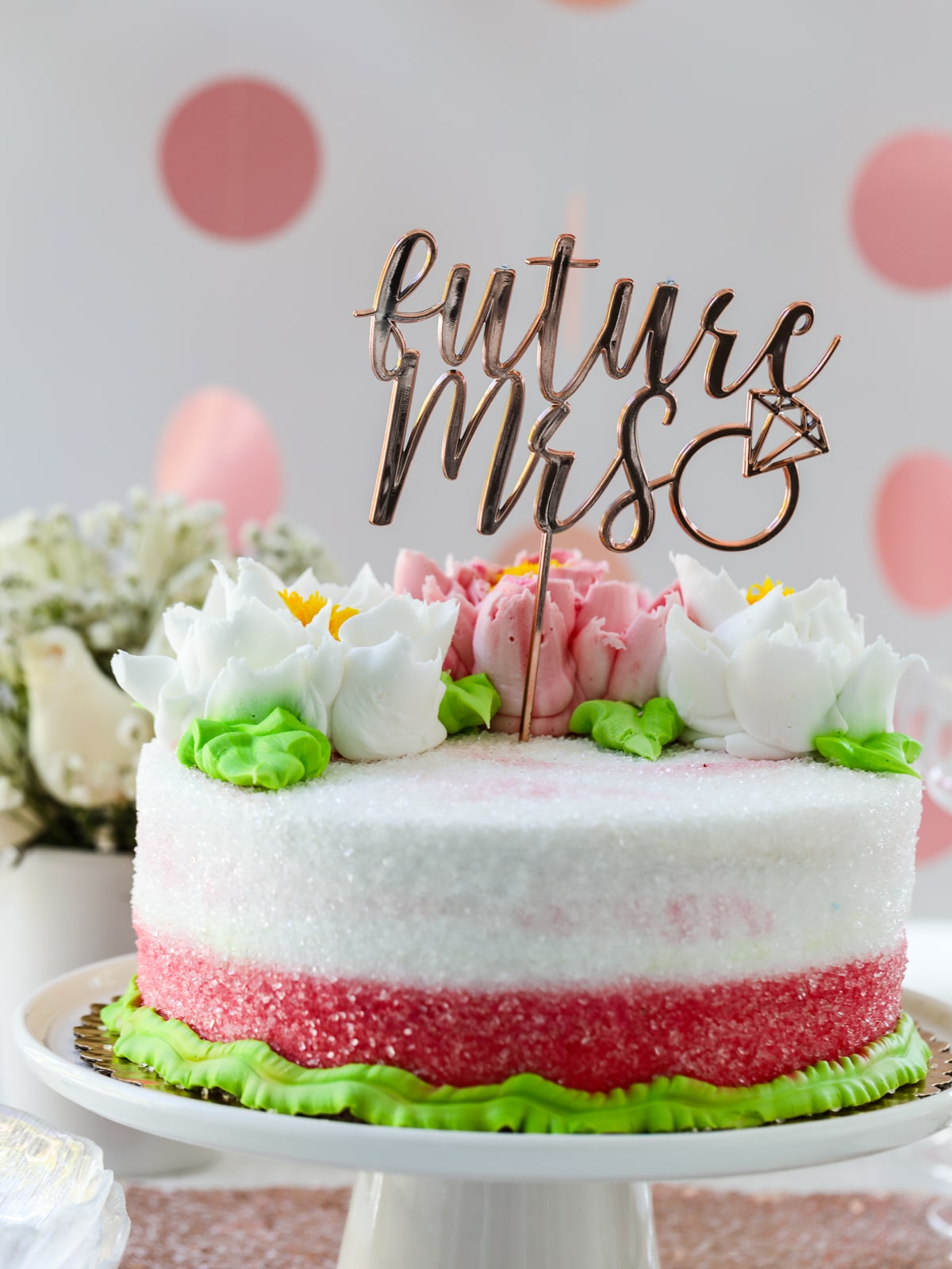A wedding shower party with a pink white and green flower cake with a decoration that says Future Mrs.