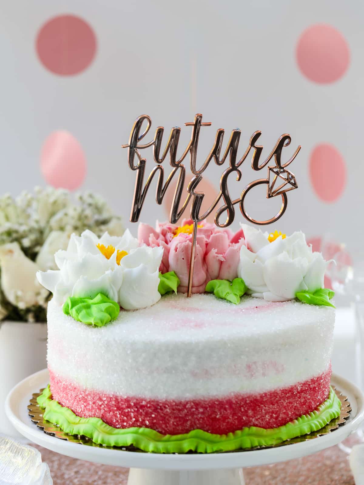 Close up of a bridal shower cake with flowers and a cake topper that says future mrs. 