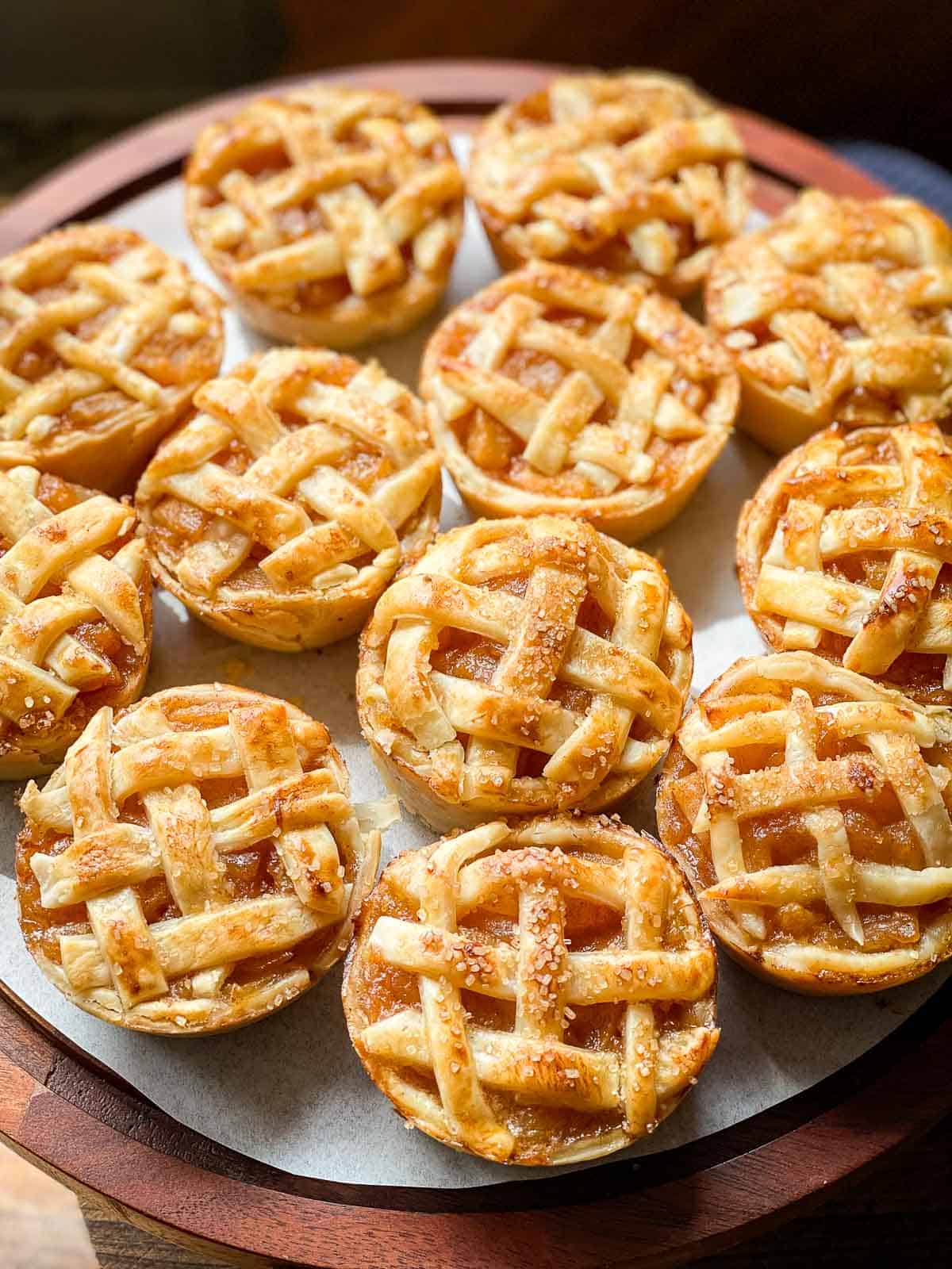 Mini round lattice apple pies on a white tray freshly baked and ready to eat. 