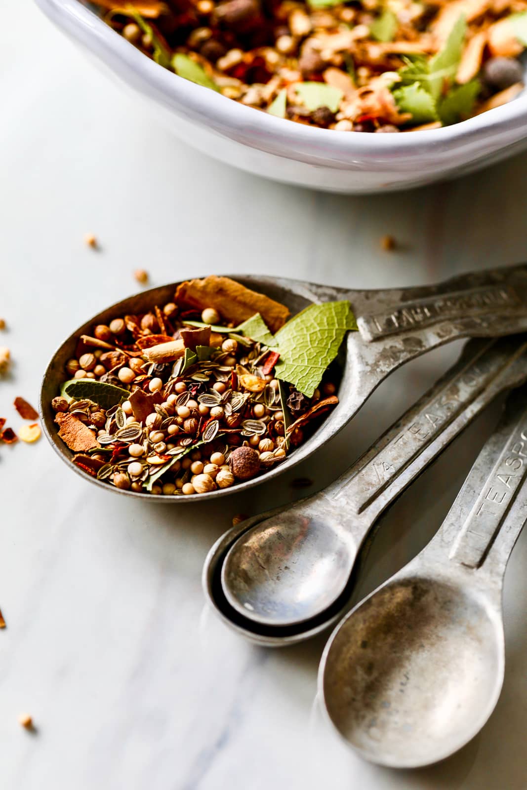 Pickling spice inside the one tablespoon measure of a set of vintage aluminum measuring spoons.