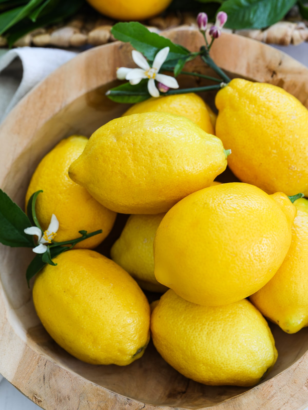 A wooden bowl filled with lemons ready to use in recipes.