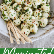 Marinated mozzarella balls in a beige dish with wooden toothpicks.