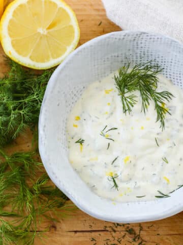 A white ceramic bowl filled with seafood sauce on a cutting board.