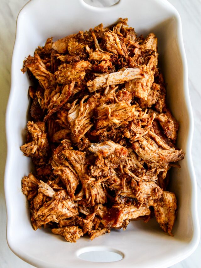 Shredded pulled pork in a white casserole dish.