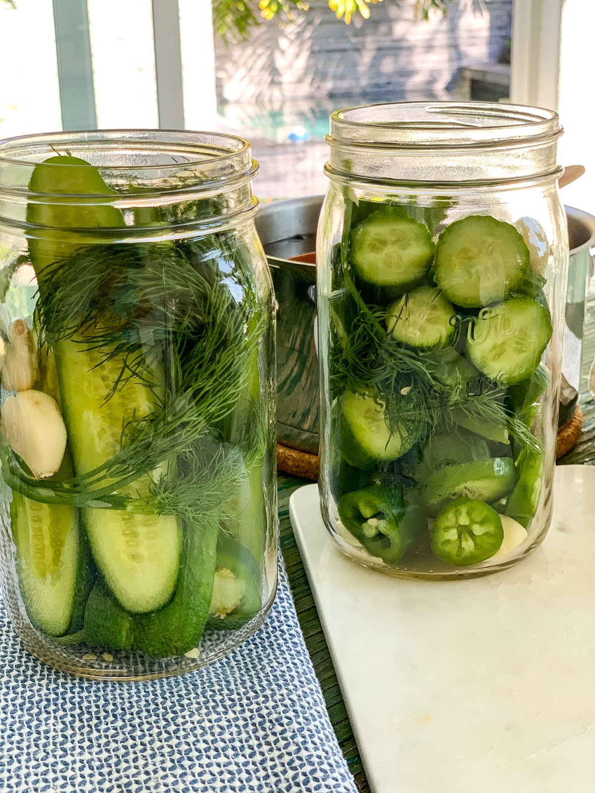 Two glass mason jars filled with dill pickle ingredients ready to add the pickling liquid.