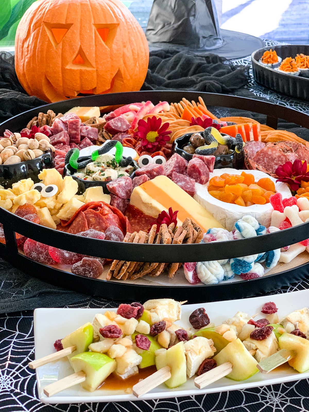 A Halloween charcuterie board loaded with cheese and meat, with some other appetizers. 