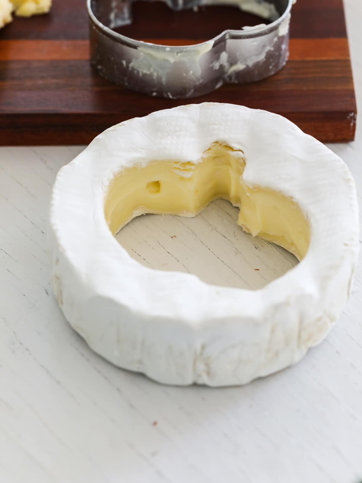 A pumpkin shape cut out of a wheel of brie for a charcuterie board.