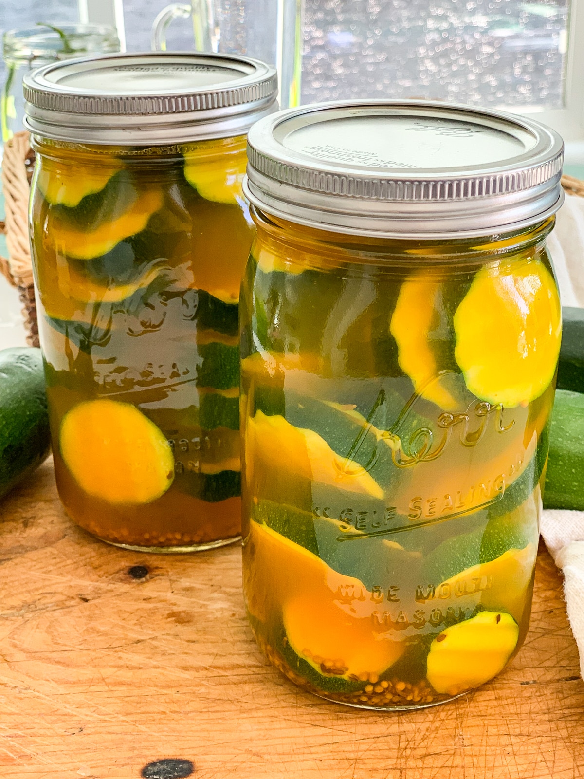 Two Mason jars filled with zucchini pickles on a cutting board. 