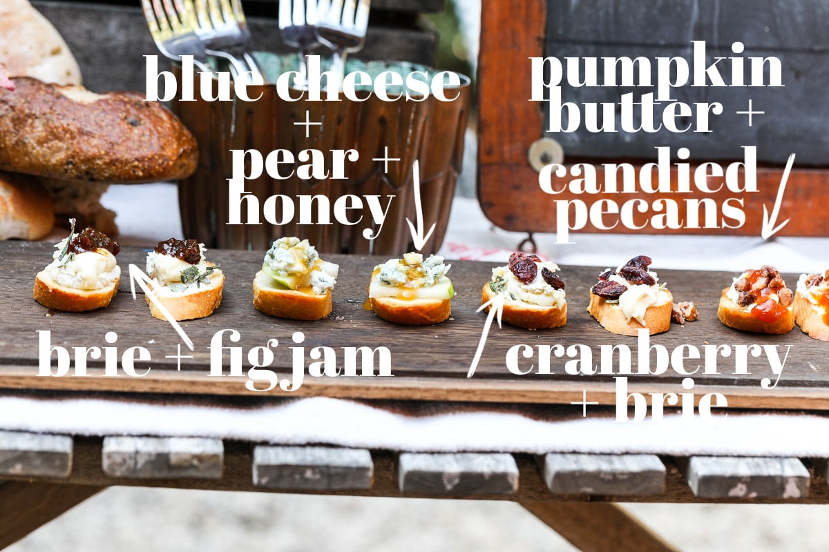 A vintage wooden board with eight small pieces of toast (or crostini) topped with fall things like pear, fig jam, brie, and pumpkin butter.