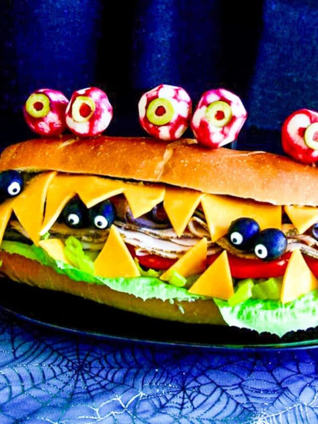 A giant sub sandwich that looks like a Monster with giant edible radish eyes and small black olive eyes.