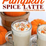 Glass cups filled with Pumpkin Spice Latte coffee drink with pumpkins in the background.