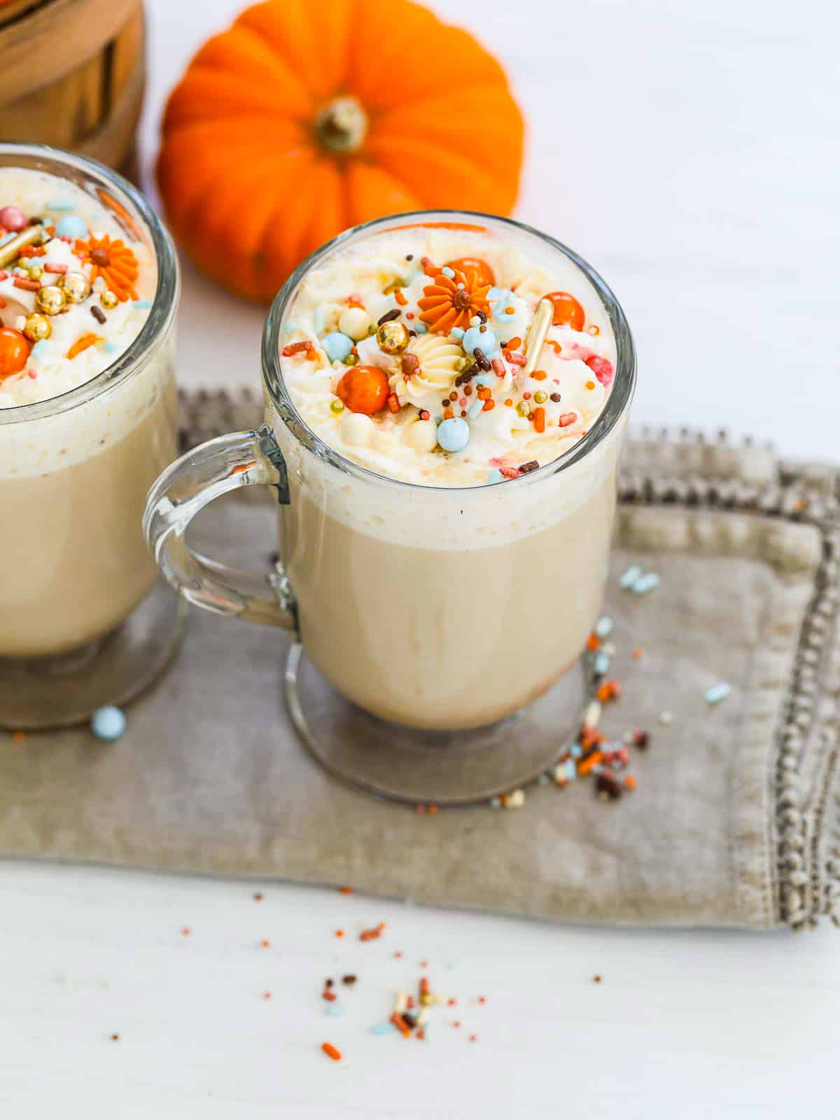 Two glass coffee mugs filled with pumpkin latte coffee drinks. 