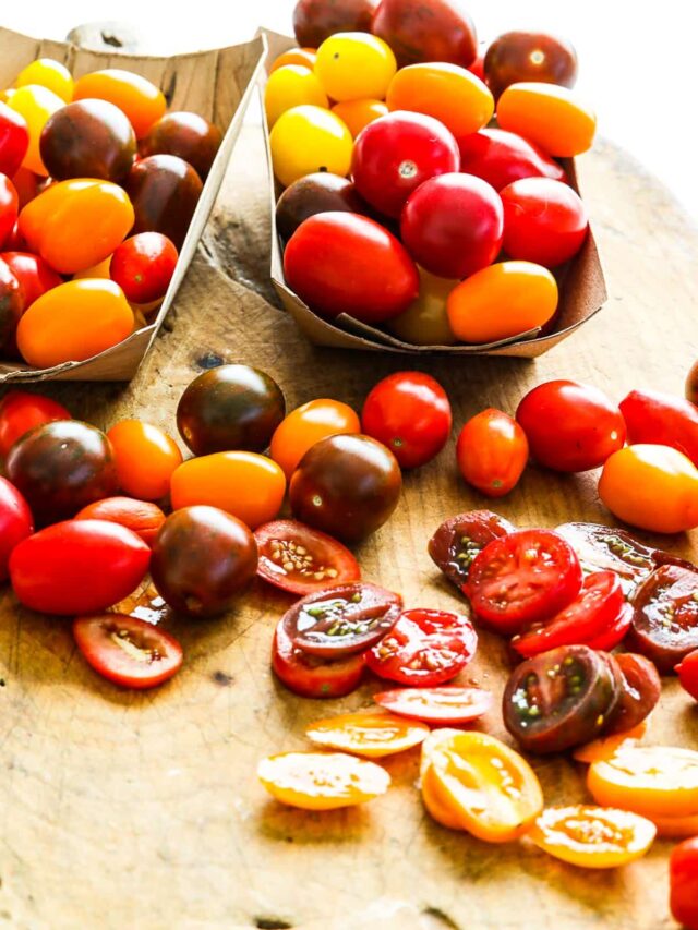Two baskets of cherry tomatoes and some cut on a board for recipes.