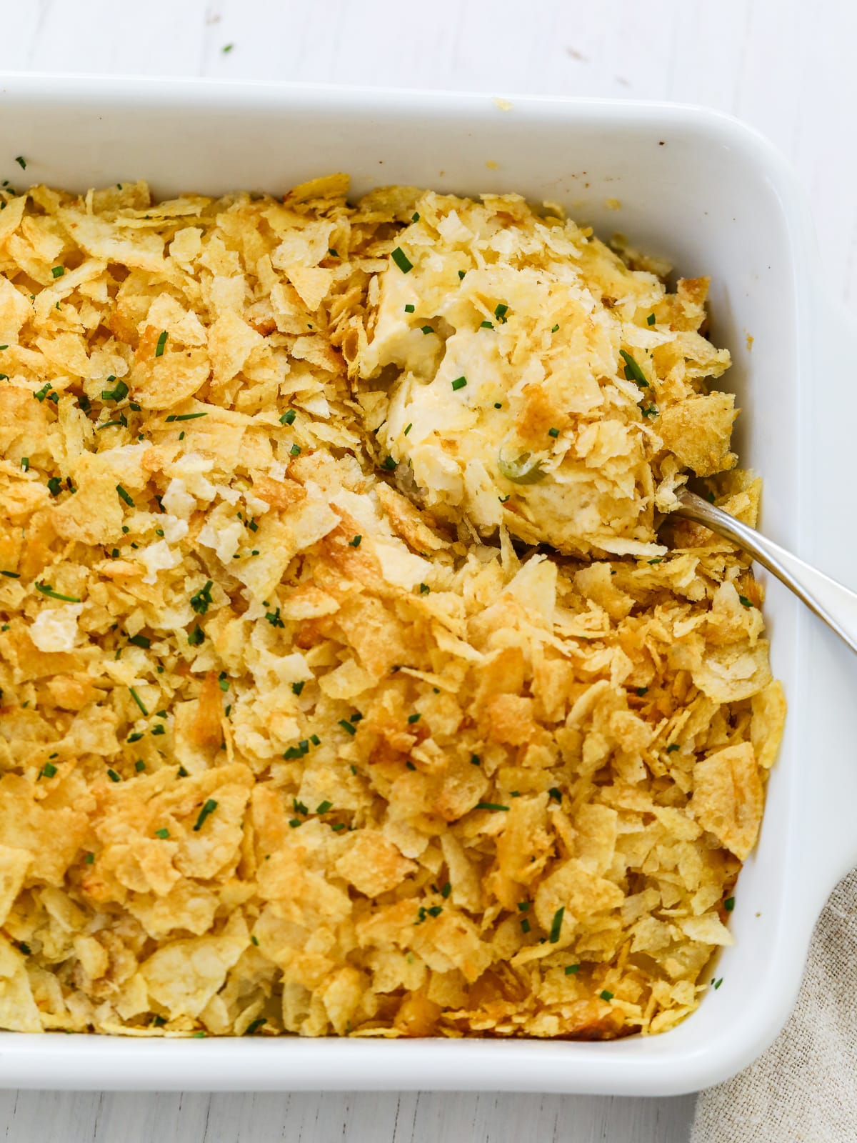 A large spoon scooping into a potato casserole dish for a holiday dinner. 