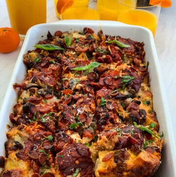 Lifting out a piece of breakfast casserole from a white baking dish with a serving utensil from the strata.