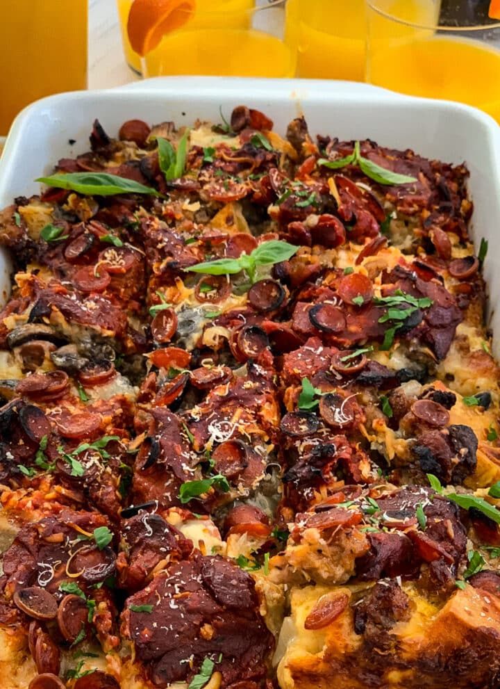 Lifting out a piece of breakfast casserole from a white baking dish with a serving utensil from the strata.