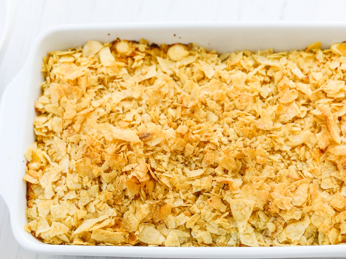 Baked potato casserole also called funeral potatoes golden brown and baked in a white casserole dish. 