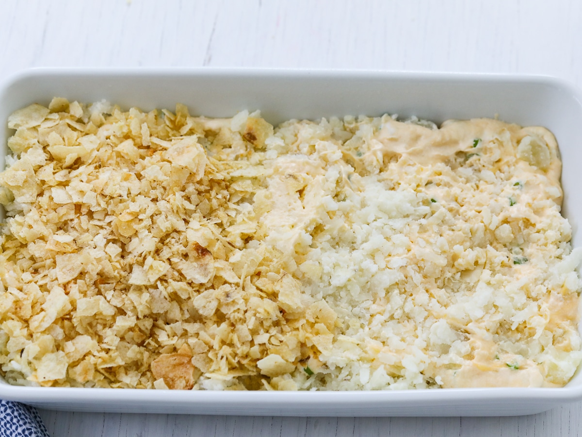 A white casserole dish with funeral potatoes and a crushed potato chip topping. 