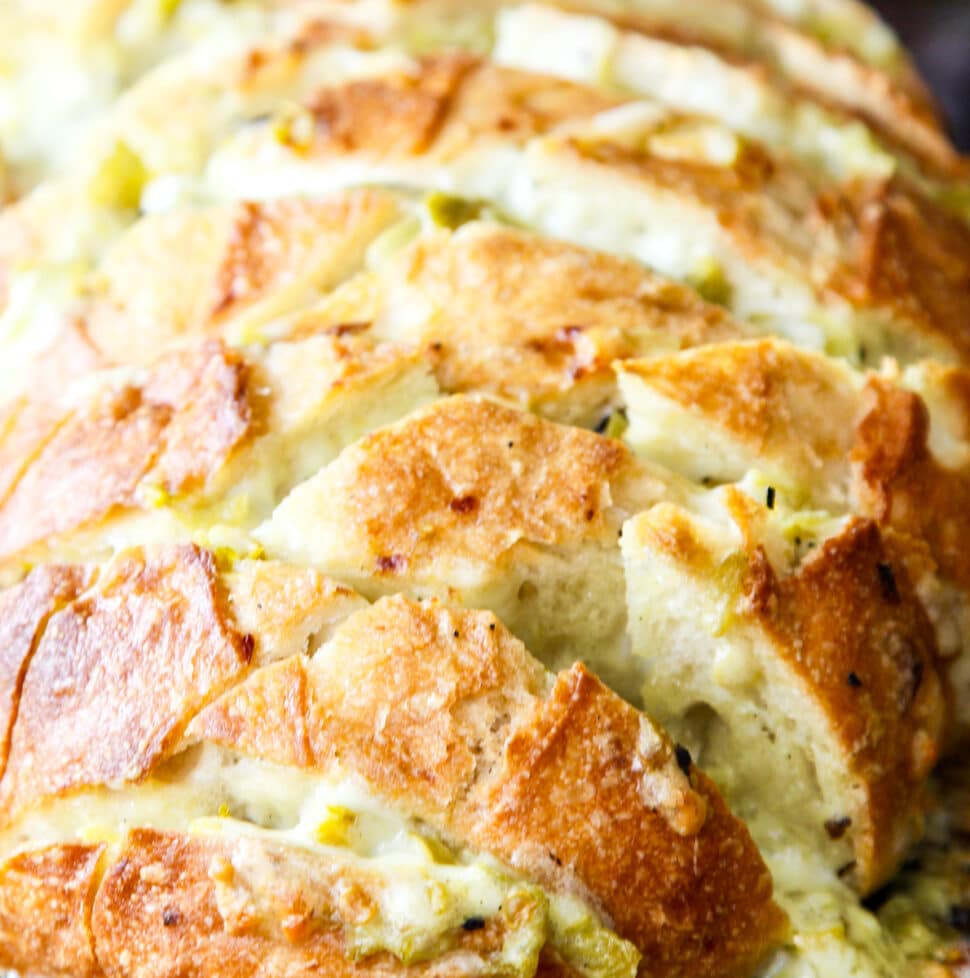 A loaf of sliced bread filled with a cheesy mixture to make a pull apart crack bread recipe.