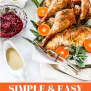 A Thanksgiving table filled with a carved turkey on a platter, mashed potatoes, cranberry sauce, and gravy.