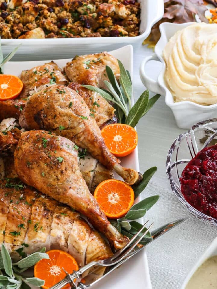 Thanksgiving dinner recipes on a table like a carved roast turkey on a platter, mashed potatoes, cranberry sauce, gravy, stuffing, and sweet potato casserole.