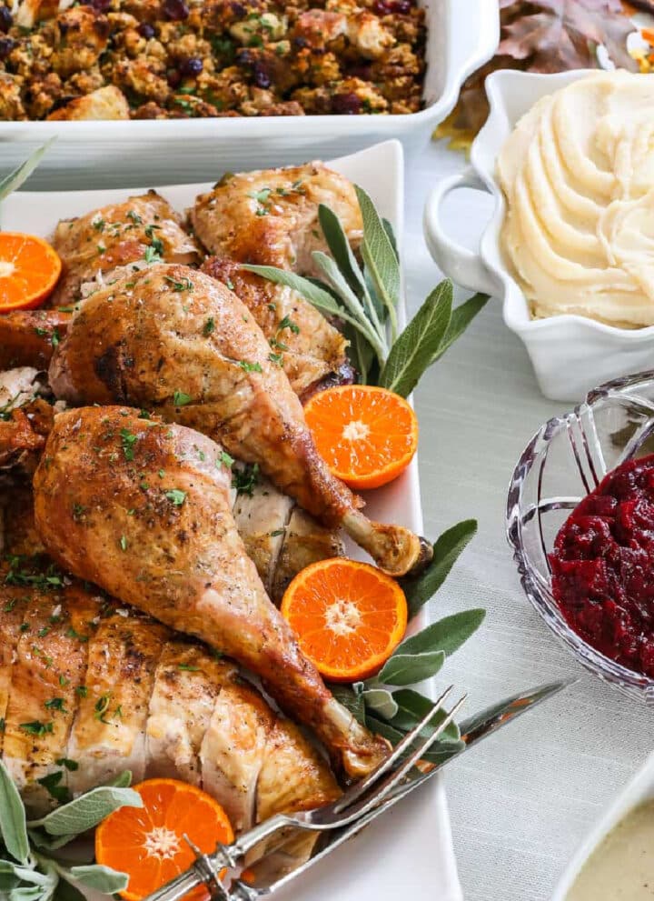 Thanksgiving dinner recipes on a table like a carved roast turkey on a platter, mashed potatoes, cranberry sauce, gravy, stuffing, and sweet potato casserole.