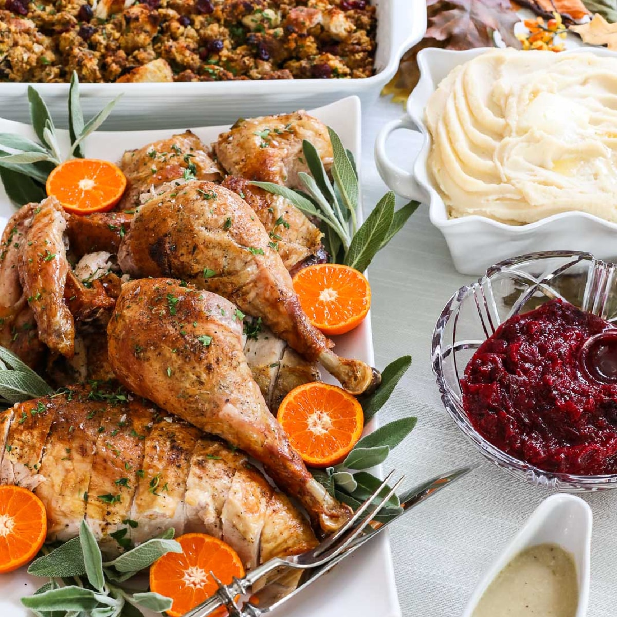 Thanksgiving dinner recipes on a table like a carved roast turkey on a platter, mashed potatoes, cranberry sauce, gravy, stuffing, and sweet potato casserole.