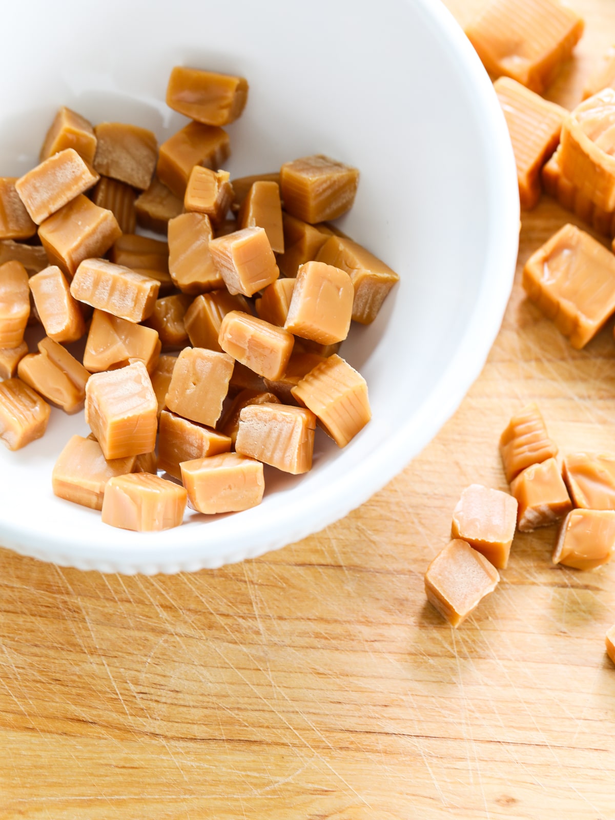 Cutting caramel candy into smaller pieces to make a caramel apple crisp. 