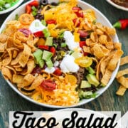 Taco Salad showing the white plate filled with the salad and topped with Fritos and grated cheese.