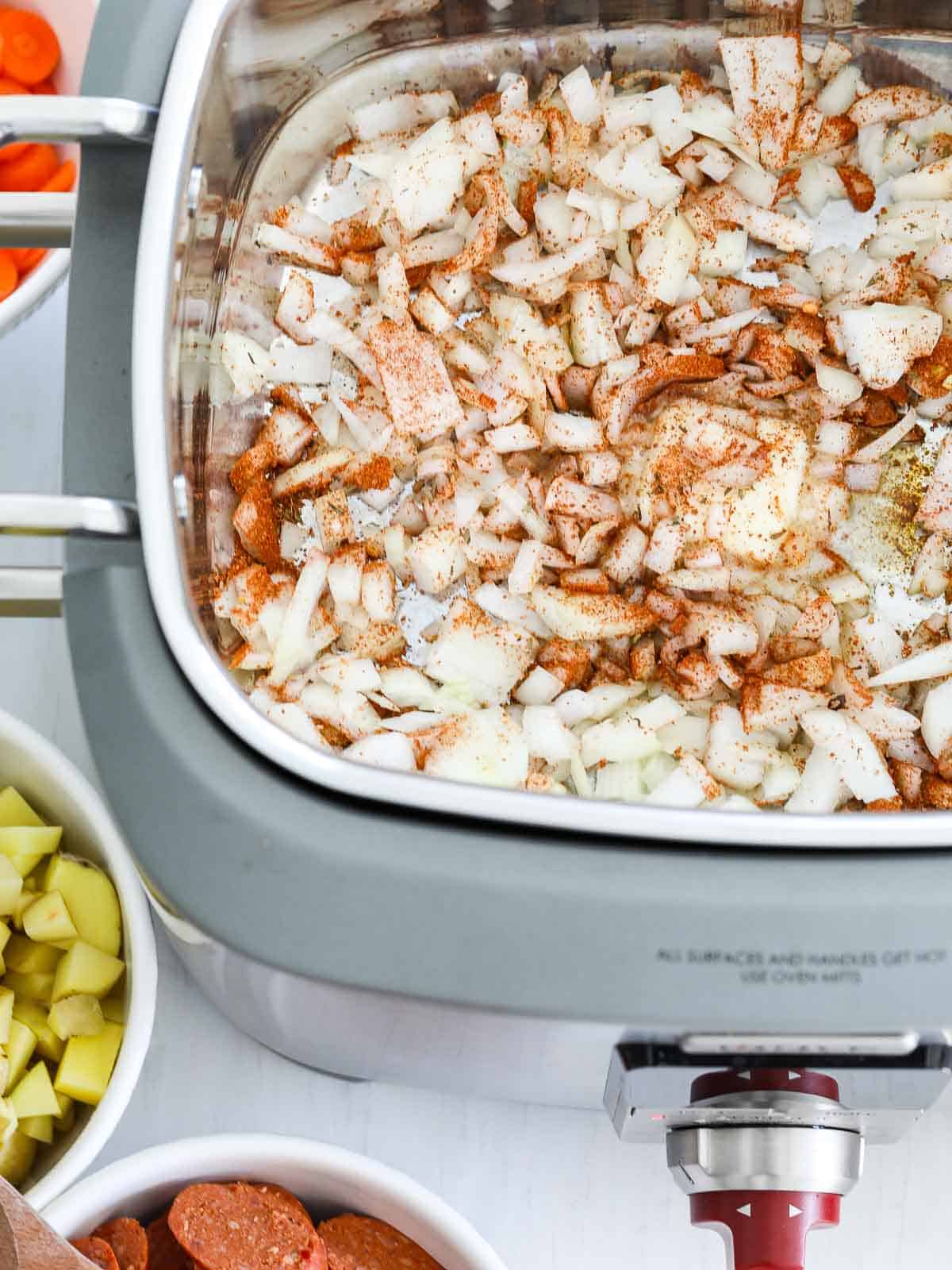 Chopped onions with butter and seasoning in a slow cooker with a saute function.
